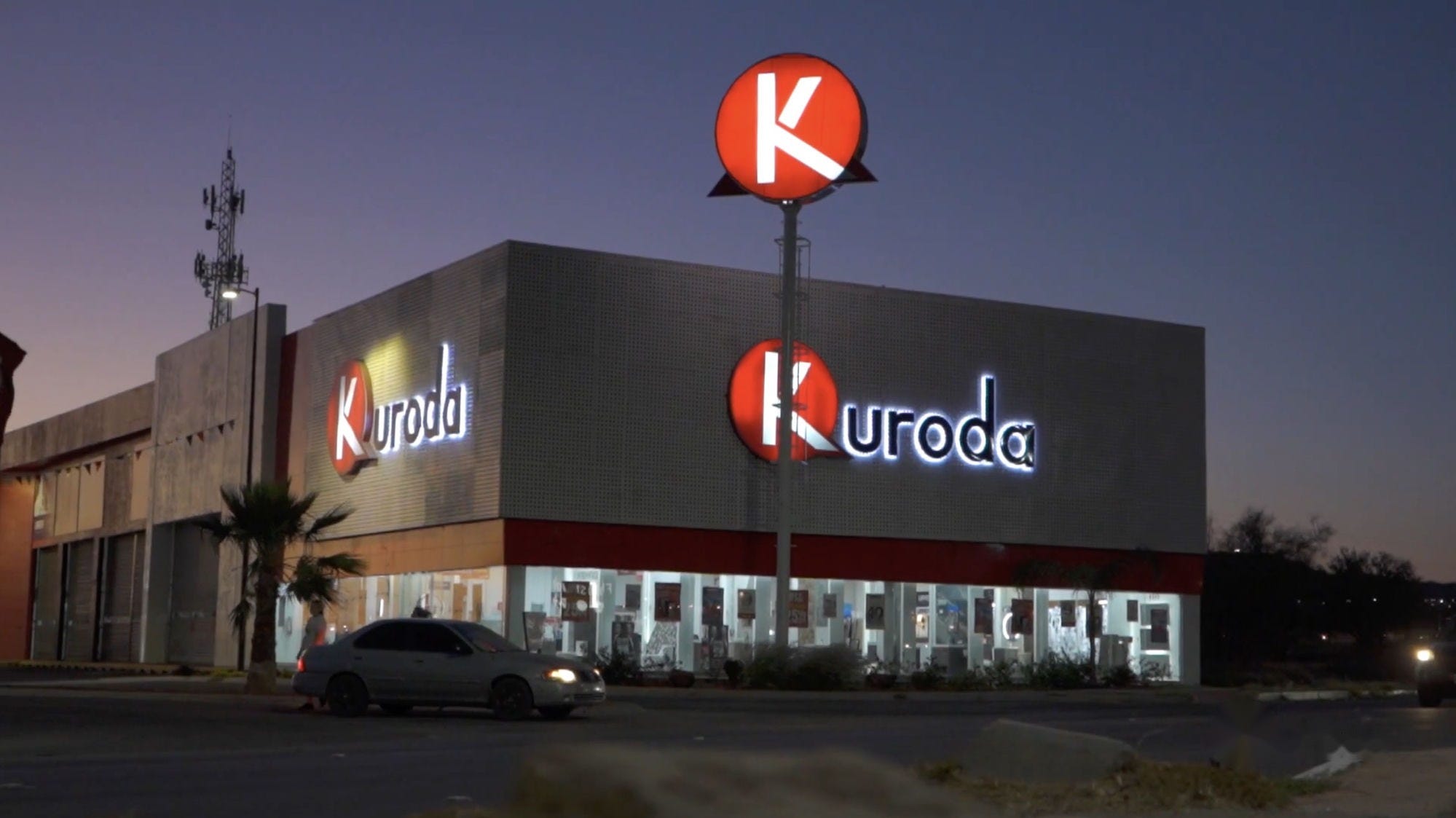 Fachada iluminada de una sucursal de Kuroda durante la noche