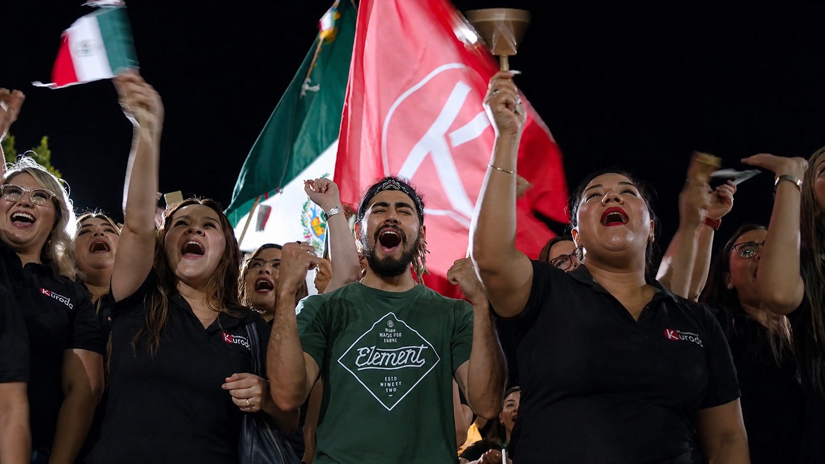 Colaboradores de Kuroda celebrando con banderas durante un evento nocturno de la empresa